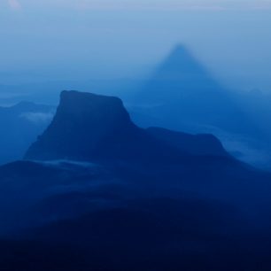 Motýlí hora vrhá svůj stín, který z horizontu sklouzává po krajině.