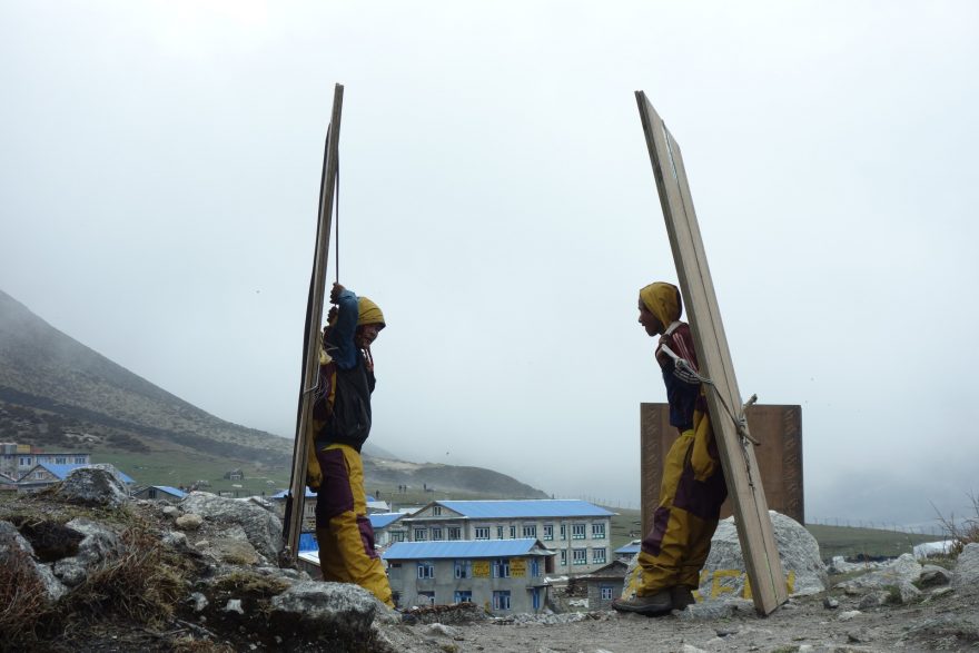 Nosiči odpočívají při transportu materiálu do oblasti, zasažené zemětřesením, Langtang, Nepál