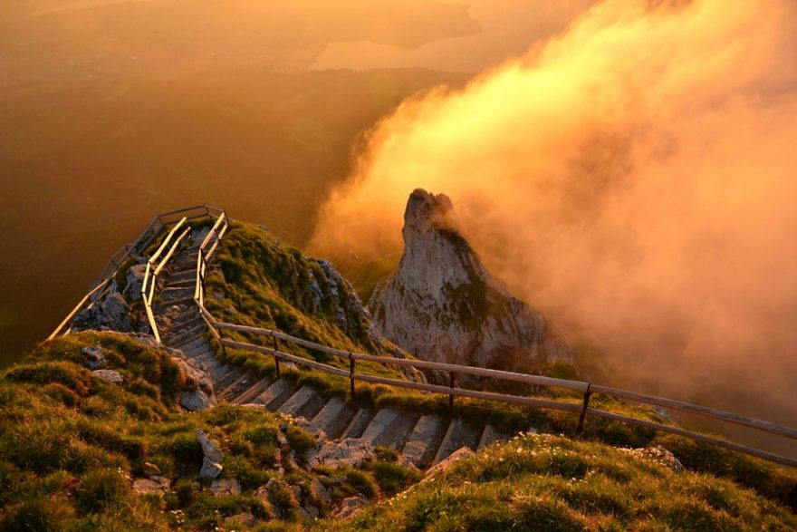 Moře mraků v oranžovém hávu halí krajinu při svítání na vrcholu Pilatus nad lucernem